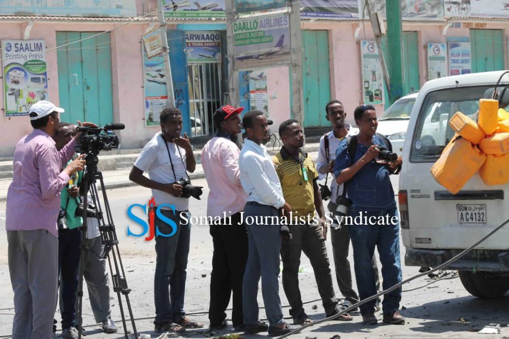 Journalists stand near a blast site in Mogadishu. | PHOTO CREDIT/SJS.