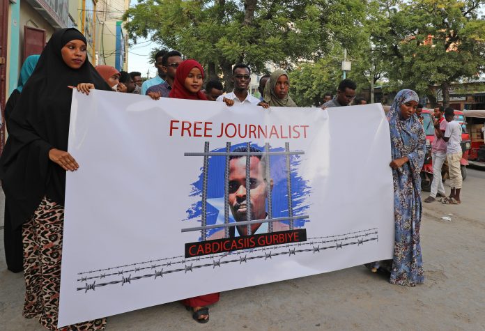 مجموعة من الصحفيين الصوماليين يحملون لافتة تحمل صورة للصحفي المسجون عبد العزيز جوربيي خلال تجمع في مقديشو يوم الجمعة 17 أبريل 2020 - مصدر الصورة: نقابة الصحفيين الصوماليين