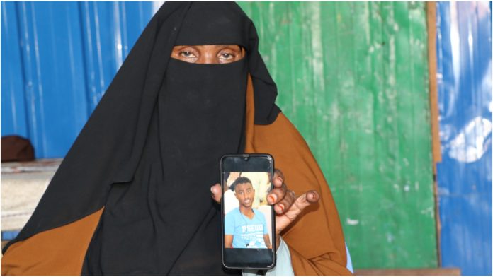 Sahra, mother of Abdirizak holds a mobile phone with the photo of her deceased son Abdirizak during an interview with SJS.