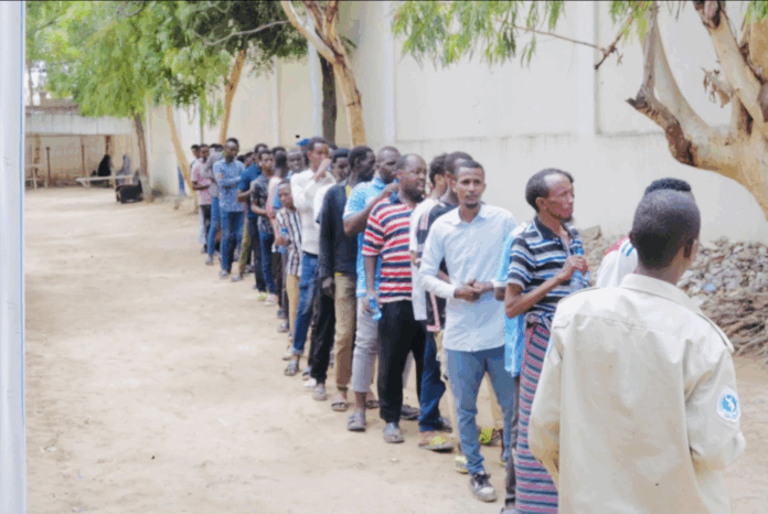 A policeman is seen standing in front of a group of people who reportedly came for voter registration in Mogadishu on 28 May 2025. | PHOTO/Facebook.